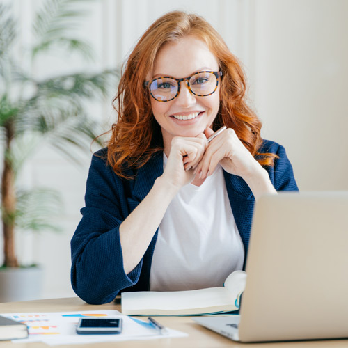 Rothaarige Frau sitzt vor Laptop
