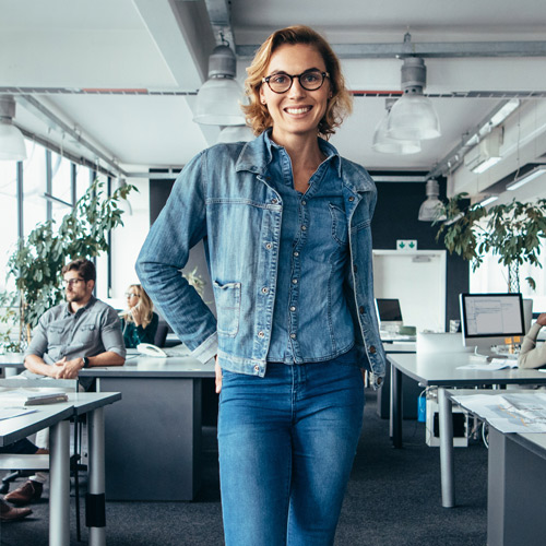 Frau in Jeans steht im Büro und lächelt