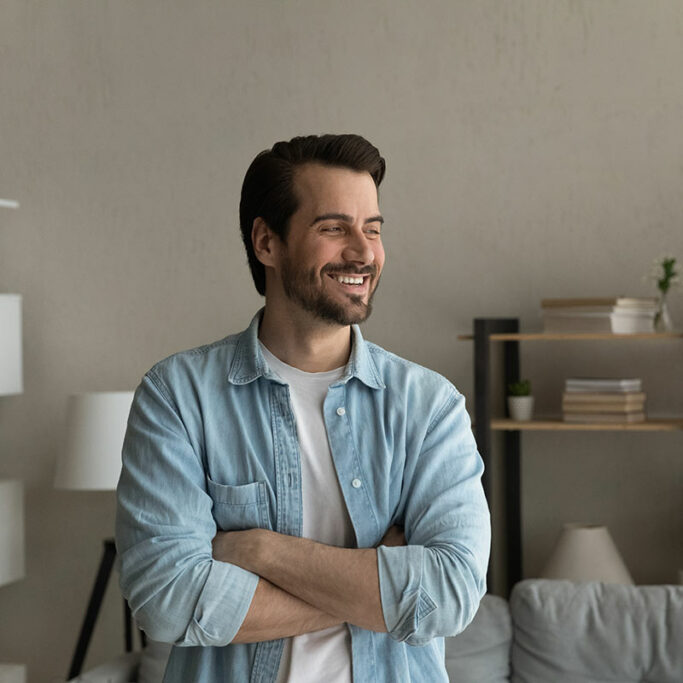 Junger Mann steht im Wohnzimmer Junger Mann steht im Wohnzimmer