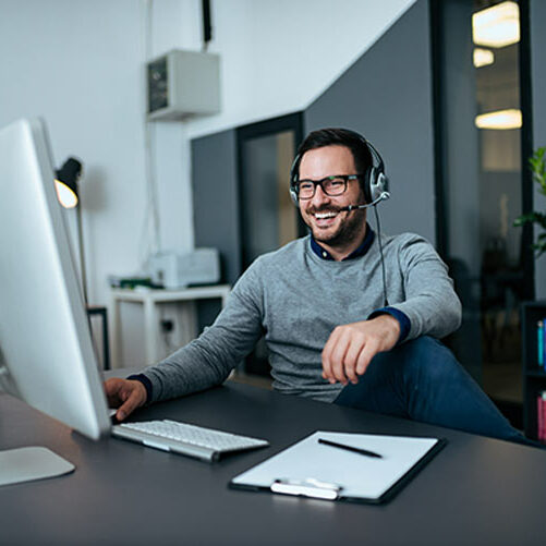 Mann sitzt im Büro und hat ein Meeting am PC Mann sitzt im Büro und hat ein Meeting am PC