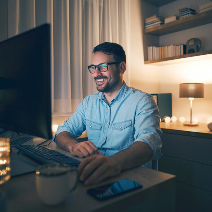 Mann mit Brille sitzt abends vor PC