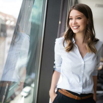 Junge Frau sieht lachend aus dem Fenster Junge Frau sieht lachend aus dem Fenster