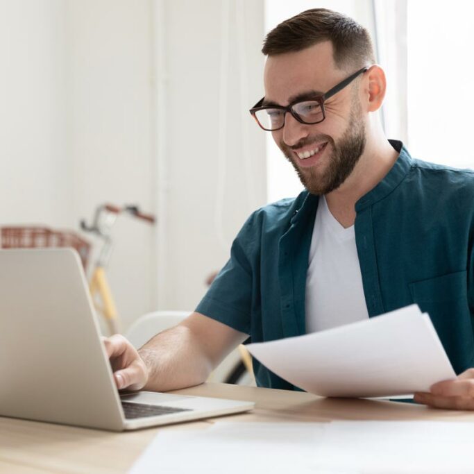 Mann mit Brille sitzt vor Laptop Mann mit Brille sitzt vor Laptop